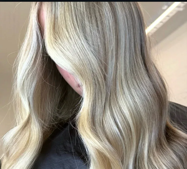 Close-up of dimensional cool-blonde waves from behind, warm salon light