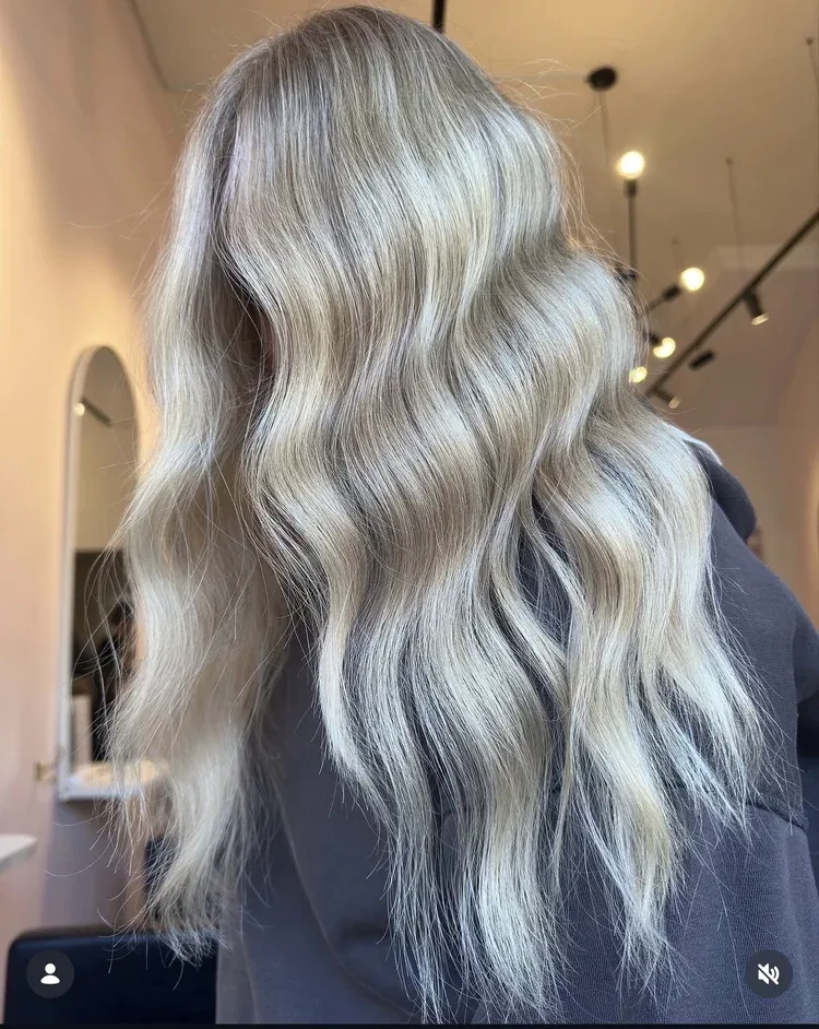 Long silver-blonde beach waves, salon interior with pendant lights